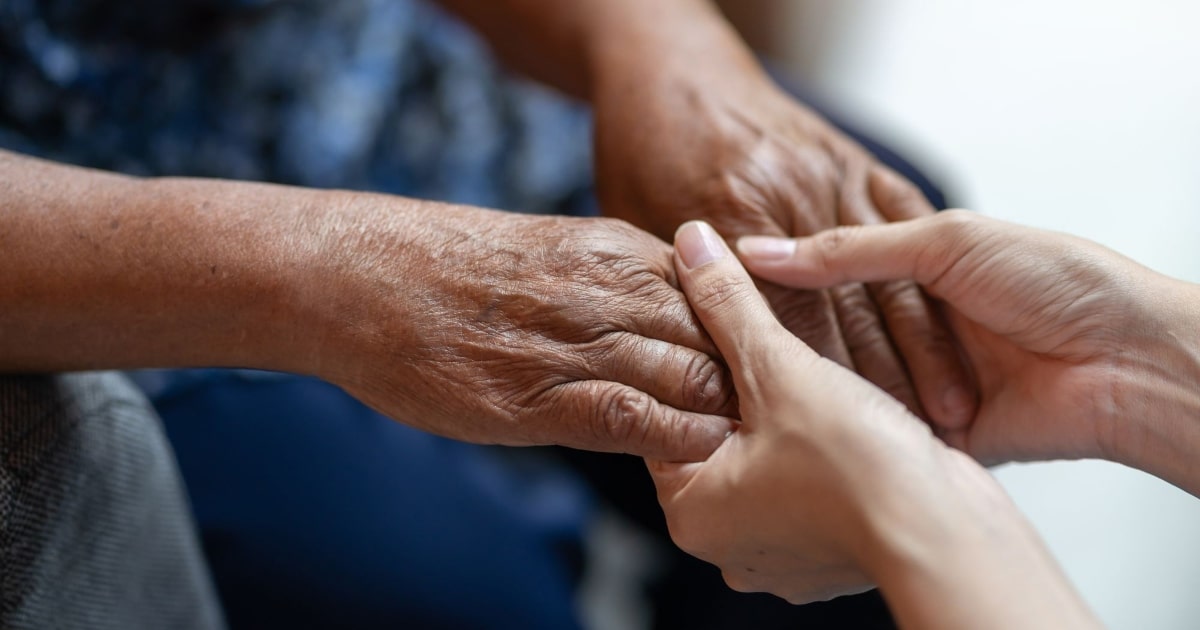 Hand-holding gesture highlighting the importance of empathy in providing end-of-life support.