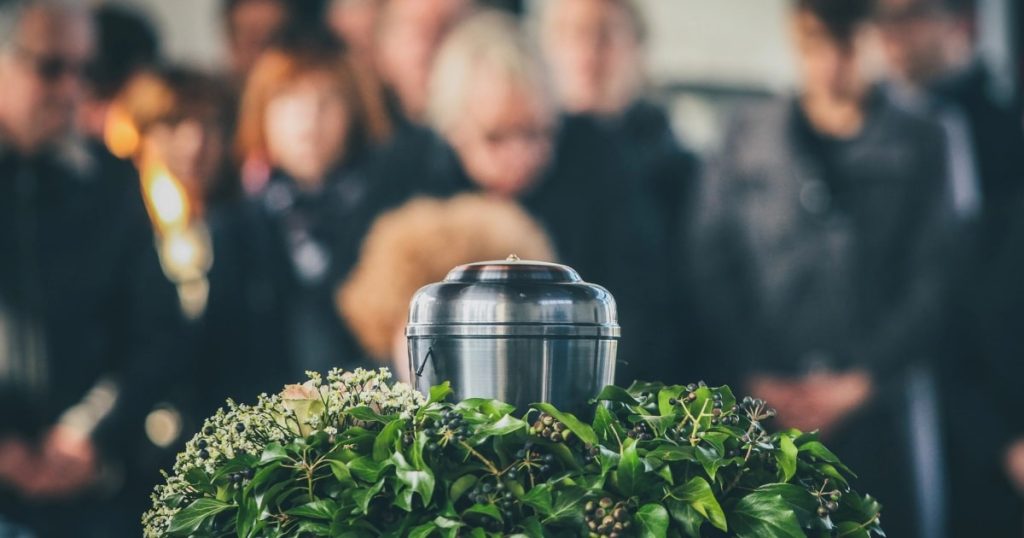 A memorial setting featuring an urn surrounded by greenery.