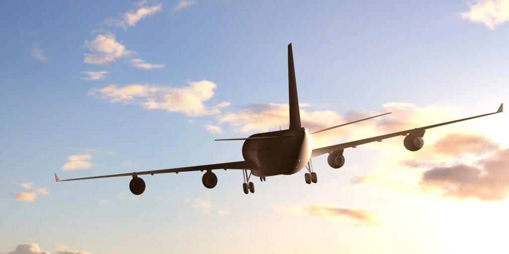 An airplane flying against a cloudy sky, symbolising the journey of transporting cremated remains. Can you bring cremated remains on a plane?