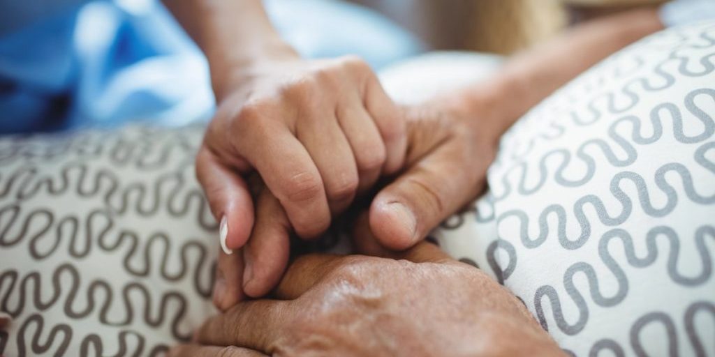 Close-up of hands offering comfort and support after a loved one’s passing, representing what to do when a person dies at home.